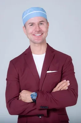 Dr. John Mesa, board-certified plastic surgeon in NYC, smiling in studio portrait.